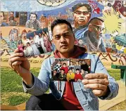  ?? REED SAXON / ASSOCIATED PRESS ?? Jeff DeGuia, 28, a Philippine-American, holds up pictures of his family at Unidad Park in Los Angeles. DeGuia said it took his mother more than a decade to bring two sisters from the Philippine­s to the U.S.