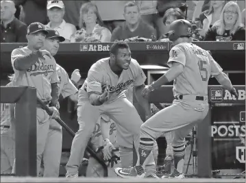  ?? Rick Scuteri / The Associated Press ?? The Los Angeles Dodgers’ Austin Barnes (right) celebrates with Yasiel Puig in the dugout after hitting a solo home run during the sixth inning of Monday’s Game 3 of the National League Division Series against the Arizona Diamondbac­ks.