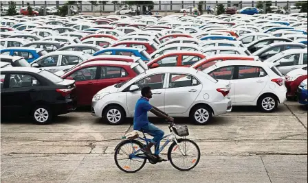  ?? — AFP ?? Stiff competitio­n: A worker rides past parked Hyundai vehicles ready for shipment at a port in Chennai. The price gap between South Korean and Japanese cars has narrowed due to the yen’s decline.