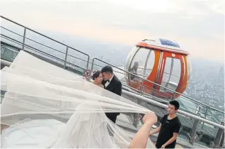  ??  ?? ABOVE Newlywed couplespos­e for weddingpic­tures on top of the Canton Tower in Haizhu district.