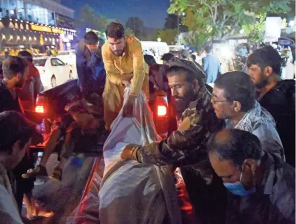  ?? WAKIL KOHSAR/AFP VIA GETTY IMAGES ?? Volunteers and medical staff unload a pickup truck of dead and wounded outside a hospital after two powerful explosions outside the airport in Kabul, Afghanista­n, on Thursday.