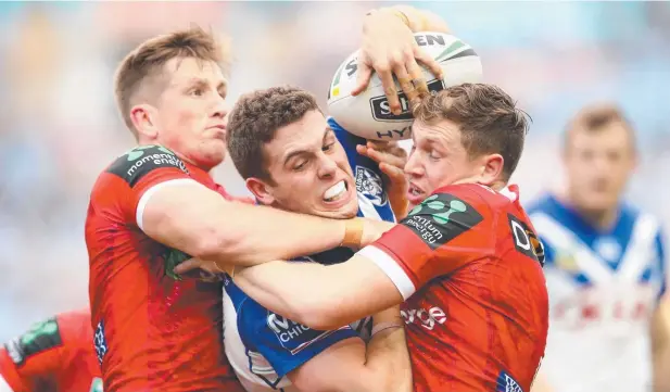  ?? Picture: GETTY IMAGES ?? NEW GAME PLAN: Bulldog Adam Elliott, here being tackled by a pair of Dragons last June, says his club is going back to an old-school approach.