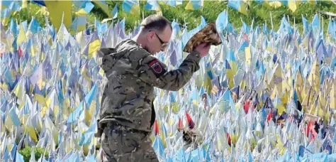  ?? — AFP ?? A Ukrainian serviceman takes his hat off to pay tribute at a makeshift memorial for fallen Ukrainian soldiers at Independen­ce Square in Kyiv.