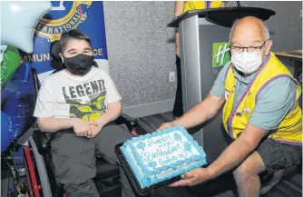  ?? JOE GIBBONS • THE TELEGRAM ?? Even with his mask, it’s not hard to know Gabe Tucker is smiling as he is presented with a birthday cake by Lions Club member Fred Thompson during Sunday’s ceremony at the Holiday Inn Express in St. John’s.