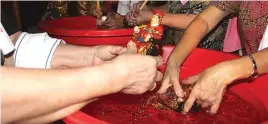  ??  ?? SUKARELA: Ibu-ibu membersihk­an patung Ma Co dengan air sabun yang dicampur teh dan kayu manis.