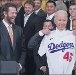  ?? JULIO CORTEZ — THE ASSOCIATED PRESS ?? Dodgers pitcher Clayton Kershaw, left, reacts as President Joe Biden holds up a jersey given to him during an event to honor the 2020World Series champions at the White House on Friday. Biden is the 46th U.S. president and his jersey reflects that.