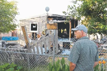  ?? Robyn Beck, AFP/Getty Images ?? Terry Brantley looks at his neighbor's home after it burnt down in an electrical fire following a magnitude 7.1 earthquake in Ridgecrest, Calif., on July 6. Brantley said he and his wife had spent the day cleaning up from the 6.4 quake on July 4 when the July 5 quake hit, severely damaging their home.