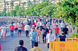  ?? — PTI ?? People walk along the sea-facing promenade at Marine Drive in Mumbai on Sunday, during the first phase of unlocking the ongoing Covid-19 nationwide lockdown.