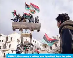  ??  ?? BENGHAZI: Libyan men on a bulldozer wave the national flag as they gather to mark the eighth anniversar­y of the uprising in Libya’s second city of Benghazi. —AFP