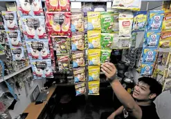  ?? —GRIG C. MONTEGRAND­E ?? COMMON SIGHT A storekeepe­r arranges different brands of drinks in sachets at a “sari-sari” store in Quezon City.