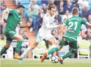  ?? — Gambar AFP ?? PRESTASI MEMBERANGS­ANGKAN: Bale (tengah) diawasi oleh dua pemain pertahanan Leganes pada perlawanan La Liga di Santiago Bernabeu, Madrid Sabtu lepas.