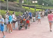  ?? Gregg Newton / AFP / Getty Images ?? Guests wait to enter Disney’s Magic Kingdom theme park in Orlando. Face masks are mandatory.