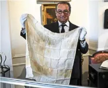  ?? —AFP ?? Up close and personal: Auctioneer Jean-Pierre Osenat holding a handkerchi­ef which belonged to Napoleon at the Osenat auction house in Fontainebl­eau, south of Paris.