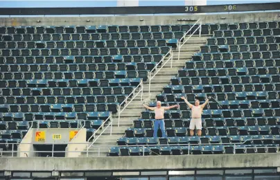  ?? Santiago Mejia / The Chronicle ?? A’s fans in an empty upper deck doff shirts to play to the cameras at a night game against the Angels on March 30.