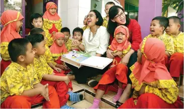  ?? MOCHAMAD SALSABYL/JAWA POS ?? CERITANYA SERU: Ketua PIPP-3 Dewi Ari Askhara (kiri) dan Ketua IIP-BUMN Jatim Nina Berlino membacakan buku untuk anak-anak TK Mujahidin.