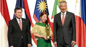  ?? —JULIE M. AURELIO ?? THE ASEANWAY Erlinda Uy Koe receives the Asean Prize at the Nov. 13 opening of the 33rd Asean Summit in Singapore. With her are Asean Secretary General Dato Lim Jock Hoi (left) and Singapore Prime Minister Lee Hsien Loong.