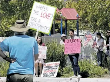  ?? Photograph­s by Myung J. Chun Los Angeles Times ?? SUPPORTERS AND CRITICS gather Sunday outside Godspeak Calvary Chapel in Newbury Park, where Pastor Rob McCoy has defied a judge’s order forbidding indoor services, sparking controvers­y and protests.