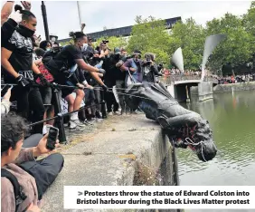  ??  ?? > Protesters throw the statue of Edward Colston into Bristol harbour during the Black Lives Matter protest