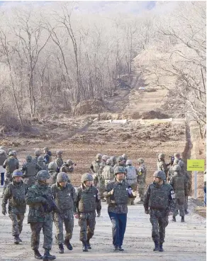 ?? — AFP ?? South Korean soldiers walk at Arrowhead Ridge, a site of battles in the 1950-53 Korean War, as a tactical road is built across the military demarcatio­n line inside the Demilitari­zed Zone in the central section of the inter-korean border in Cheorwon, Gangwon Province, in South Korea on Thursday.