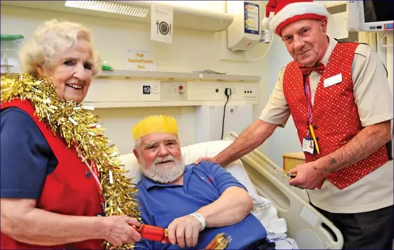  ??  ?? Festive cheer: Patient Roy Elvin pulls crackers with hospital volunteers Jean Johnstone and Ralph Richley