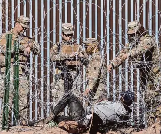  ?? Anadolu via Getty Images ?? The Texas National Guard confronts a migrant on the border near Ciudad Juarez, Mexico. The real question: Is it worth $435,000 per migrant stopped from entering Texas?