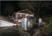  ?? (Stephen B. Thornton/The Arkansas Democrat-Gazette via AP) ?? Path of Destructio­n: In this Tuesday photo, Jim Reed walks past an overturned car and a detached roof, left, at a home along Holiday Terrace in Higginson, Ark., after a storm passed through the White County town.