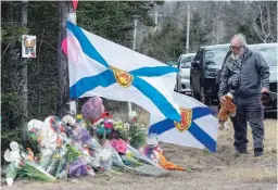  ?? ANDREW VAUGHAN THE CANADIAN PRESS ?? A man pays his respects at a roadside memorial for the victims of Canada’s worst mass shooting in Portapique, N.S., on Thursday.