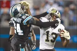  ?? The Associated Press ?? New Orleans Saints’ Michael Thomas (13) and Carolina Panthers’ James Bradberry (24) grab each other’s face masks during NFL action in Charlotte, N.C., on Monday night.