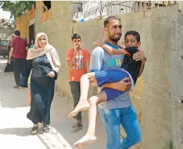  ?? SAID KHATIB/GETTY-AFP ?? A Palestinia­n man carries an injured boy following an Israeli airstrike Saturday in the Gaza Strip, during the territory’s worst escalation of violence since last year.