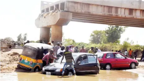  ?? Photo: NAN ?? Motorists under a bridge blown-up by Boko Haram members in 2014 at Askira-Uba Local Government Area of Borno State during the weekend. The bridge’s reconstruc­tion contract has been awarded by the federal government and Minister of State for Power, Works and Housing, Mustapha Baba-Shehuri inspected the area.