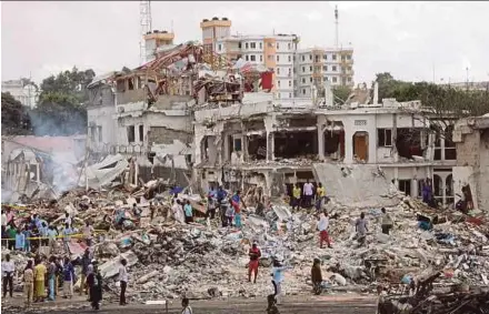  ?? REUTERS PIC ?? Somali government forces and people gathering at the scene of a truck bomb explosion in the Hodan district of Mogadishu yesterday.