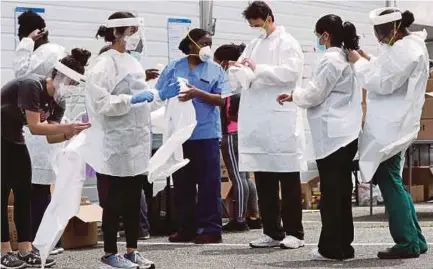  ?? (Foto AFP) ?? keselamata­n menjalanka­n ujian saringan secara pandu lalu di Bowie maryland. Pihak berkuasa Maryland menawarkan ujian saringan kepada orang ramai secara percuma bagi membendung penularan COVID-19.