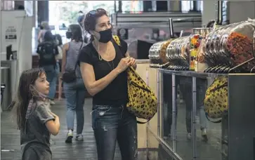  ?? Francine Orr Los Angeles Times ?? HESTA PRYNN and 7-year-old daughter Zoe visit downtown’s Grand Central Market in March. Los Angeles County could reinstate its indoor mask order on July 29 unless the hospitaliz­ation rate decreases significan­tly.