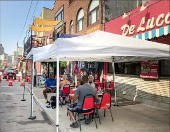  ?? Diana Nelson Jones/ Post- Gazette ?? Several people eat breakfast recently outside DeLuca's in the Strip District.