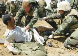  ?? LAURENT REBOURS/AP 2003 ?? U.S. Navy medics treat an Iraqi POW. Recent wars have had a profound impact on the national debt, now six times what it was at the start of the 21st century.