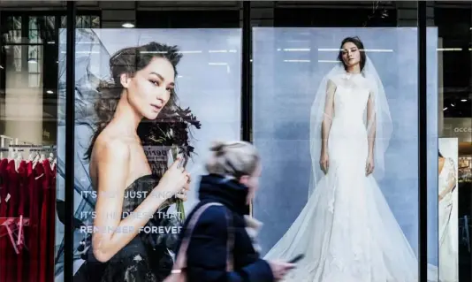  ?? Jeenah Moon/Bloomberg ?? A pedestrian passes in front of a David's Bridal store last week in New York. The chain isn’t planning to close stores or interrupt operations as it files for bankruptcy.