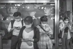  ?? KEVIN FRAYER/GETTY IMAGES ?? Chinese commuters look at their mobile phones as they wait at a bus stop on Sept. 21, 2020, in Beijing.