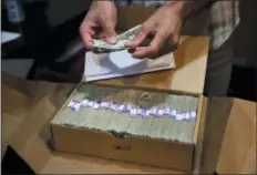  ?? THE ASSOCIATED PRESS ?? In this June 27, 2017 file photo, the proprietor of a medical marijuana dispensary prepares his monthly tax payment, over $40,000 in cash, at his Los Angeles store. A proposal in Congress to ease the federal ban on marijuana could encourage more banks to do business with cannabis companies, but it appears to fall short of a cure-all for an industry that must operate mainly as a cash business in a credit card world.