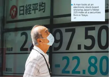  ?? AP ?? A man looks at an electronic stock board showing Japan’s Nikkei 225 index at a securities firm in Tokyo.