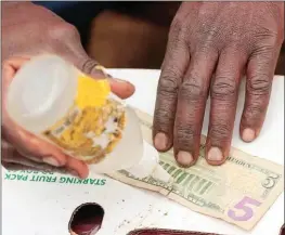  ?? ?? A black market trader repairs a torn US banknote outside a shopping centre in Kuwadzana, Harare