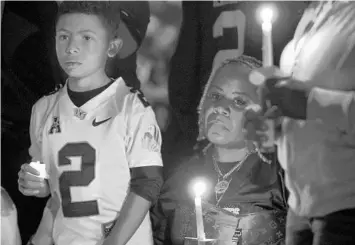  ?? WILLIE J. ALLEN JR./ORLANDO SENTINEL ?? Denise Anderson, right, sits next to a big fan of her son’s, Miles Morning, in front of the hundreds of people that came to the “One Last Knight Walk” for slain former UCF Knight Otis Anderson Jr. on Saturday. Anderson died by the hand of his father earlier in the week.