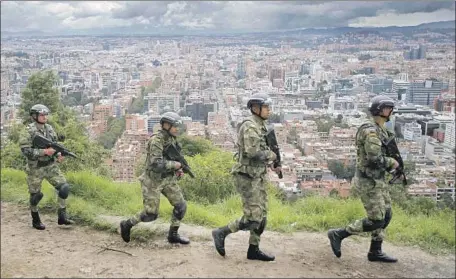  ?? Fernando Vergara Associated Press ?? SOLDIERS PATROL the outskirts of Bogota, Colombia, the day before the presidenti­al election, which is expected to go to a runoff.