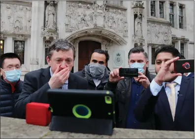  ?? (AP/Frank Augstein) ?? Uber drivers of the App Drivers & Couriers Union listen to the court decision on a tablet computer Friday outside the Supreme Court in London.