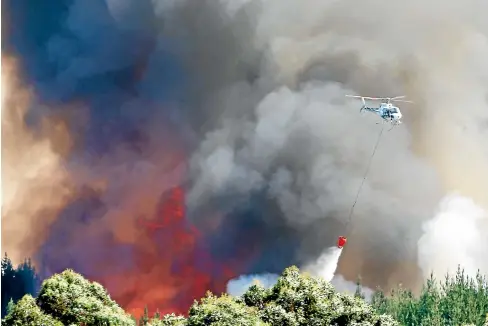  ?? GETTY IMAGES ?? A chopper dumps water as the forest fire continues to burn on Thursday. With a total of 22 helicopter­s, it is the biggest aerial firefighti­ng operation in New Zealand history.