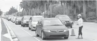  ?? WAYNE K. ROUSTAN/SUN SENTINEL ?? Cars lined up over five miles and people waited more than three hours to get free groceries in Miramar.