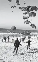  ?? AFP VIA GETTY IMAGES ?? This image grab from an AFPTV video shows Palestinia­ns running toward parachutes attached to food parcels, air-dropped from U.S. aircrafts on a beach in the Gaza Strip on March 2.