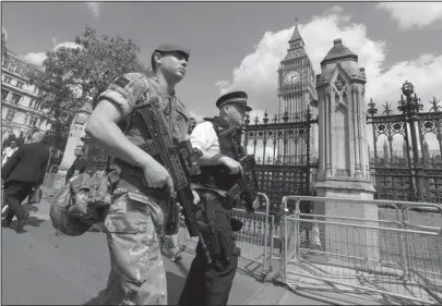  ?? The Associated Press ?? ON GUARD: A member of the army joins police officers Wednesday in Westminste­r, London. Britons will find armed troops at vital locations Wednesday after the official threat level was raised to its highest point following a suicide bombing that killed...
