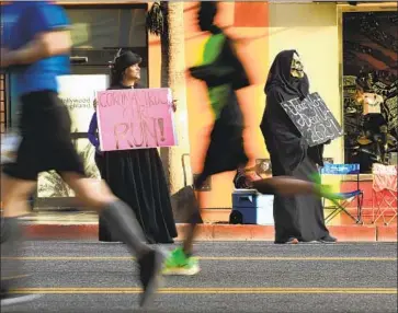  ?? Photog r aphs by Wally Skalij Los Angeles Times ?? THE MARCH 8 L. A. Marathon was run against the backdrop of the rising menace of the coronaviru­s, as this couple showed along Hollywood Boulevard. Even race organizers were unsure the event would come off.