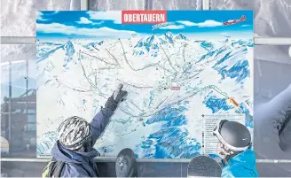  ??  ?? READY FOR ACTION: Snowboarde­rs at Obertauern check a map of slopes at ZehnerkarB­ergstation in the Austrian Alps, a favourite destinatio­n for winter sports lovers.