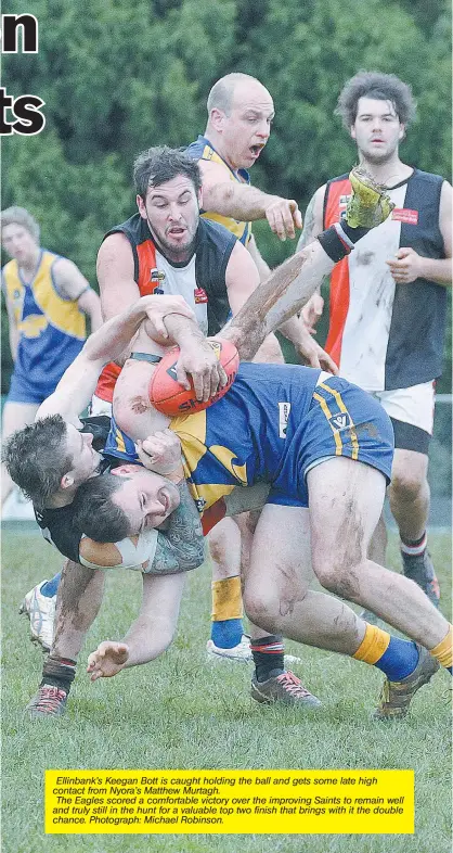  ??  ?? Ellinbank’s Keegan Bott is caught holding the ball and gets some late high contact from Nyora’s Matthew Murtagh. The Eagles scored a comfortabl­e victory over the improving Saints to remain well and truly still in the hunt for a valuable top two finish...